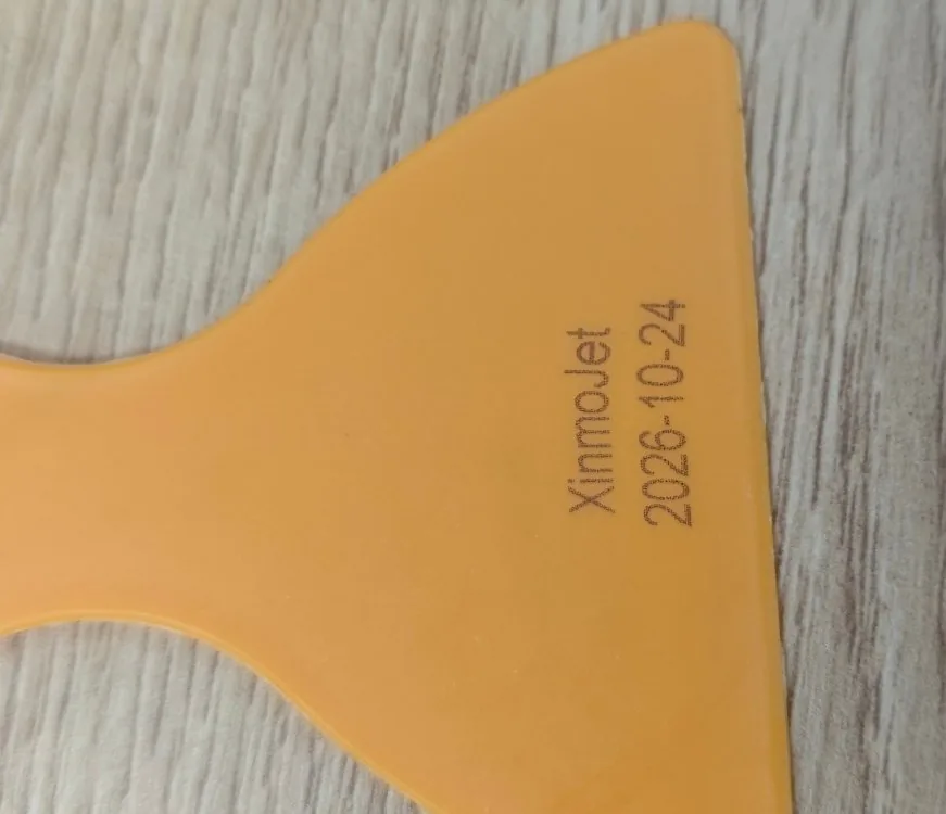 The brand name XinmoJet and the date 2026-10-24 printed as two lines on the flat face of an orange moulded plastic part