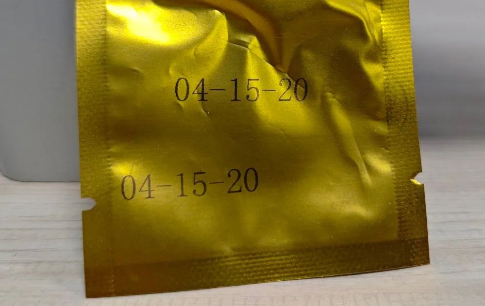 Two identical two-line date codes printed on a crumpled gold aluminium foil pouch
