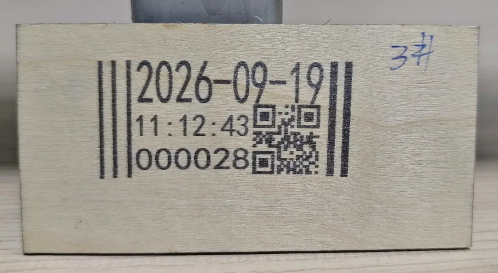 A date, a time and a running count printed on a machined plywood block with visible grain and glue lines